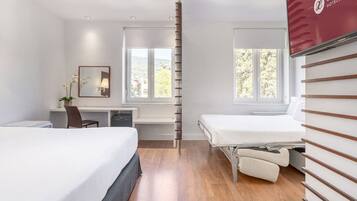 Habitación de hotel con dos camas, un escritorio, una silla y ventana con vistas a árboles.