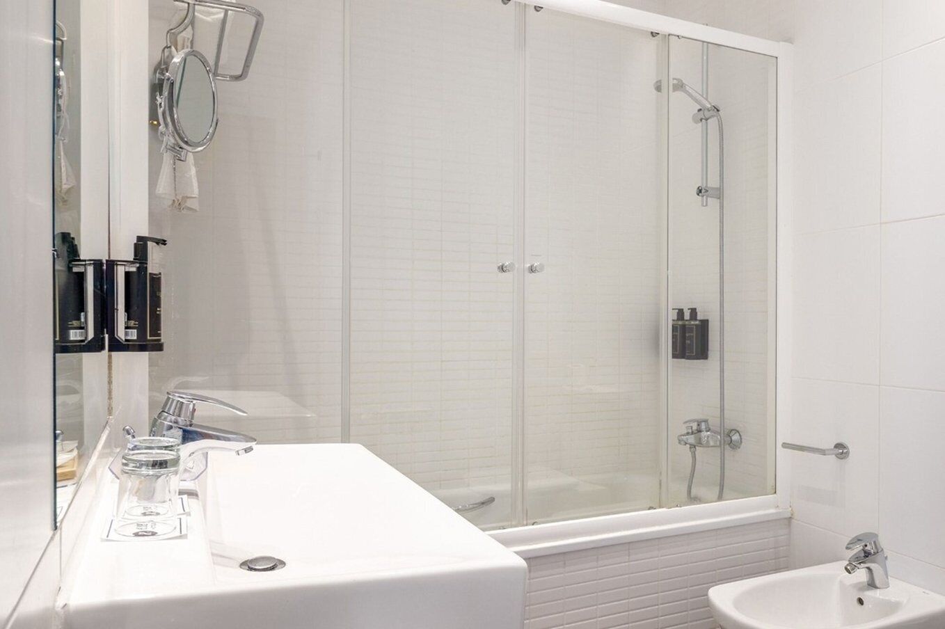 A modern bathroom with a glass-enclosed shower, a white sink, and a mirror.