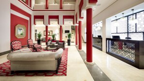 Un vestíbulo amplio con techo alto, decoración en rojo y blanco, un sofá confortable y una escalera que conduce a los pisos superiores.