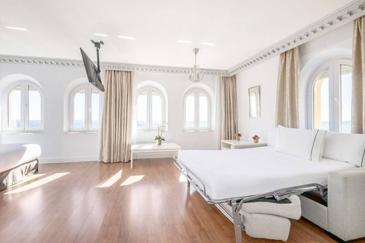 Une chambre d’hôtel spacieuse, dotée d’un grand lit, d’un bureau et d’un téléviseur fixé au mur.