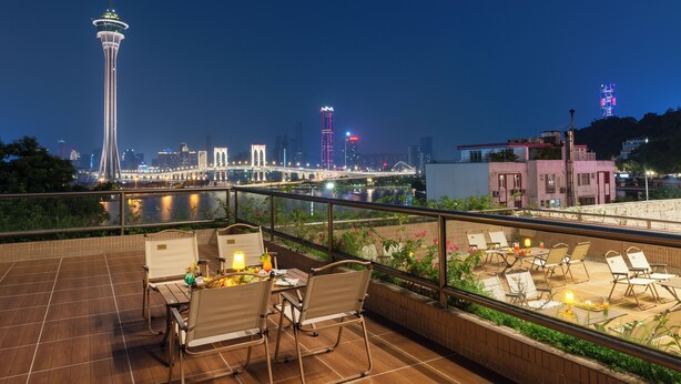 A rooftop terrace with outdoor seating and a view of the city skyline at night. - Riviera Hotel Macau (Macau)