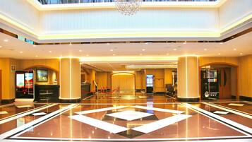 A spacious lobby with a polished floor, a reception desk, and a coffee shop.