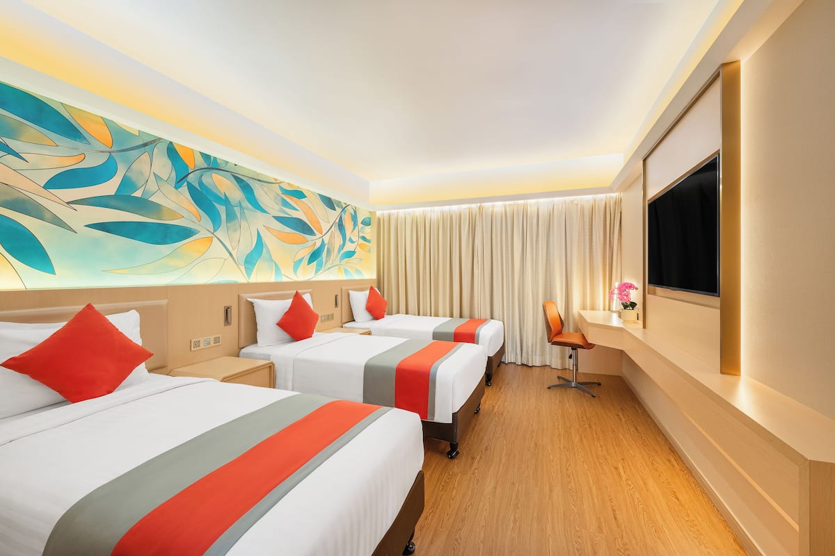 A hotel room with three beds, a TV, a desk, and a large abstract painting on the wall.