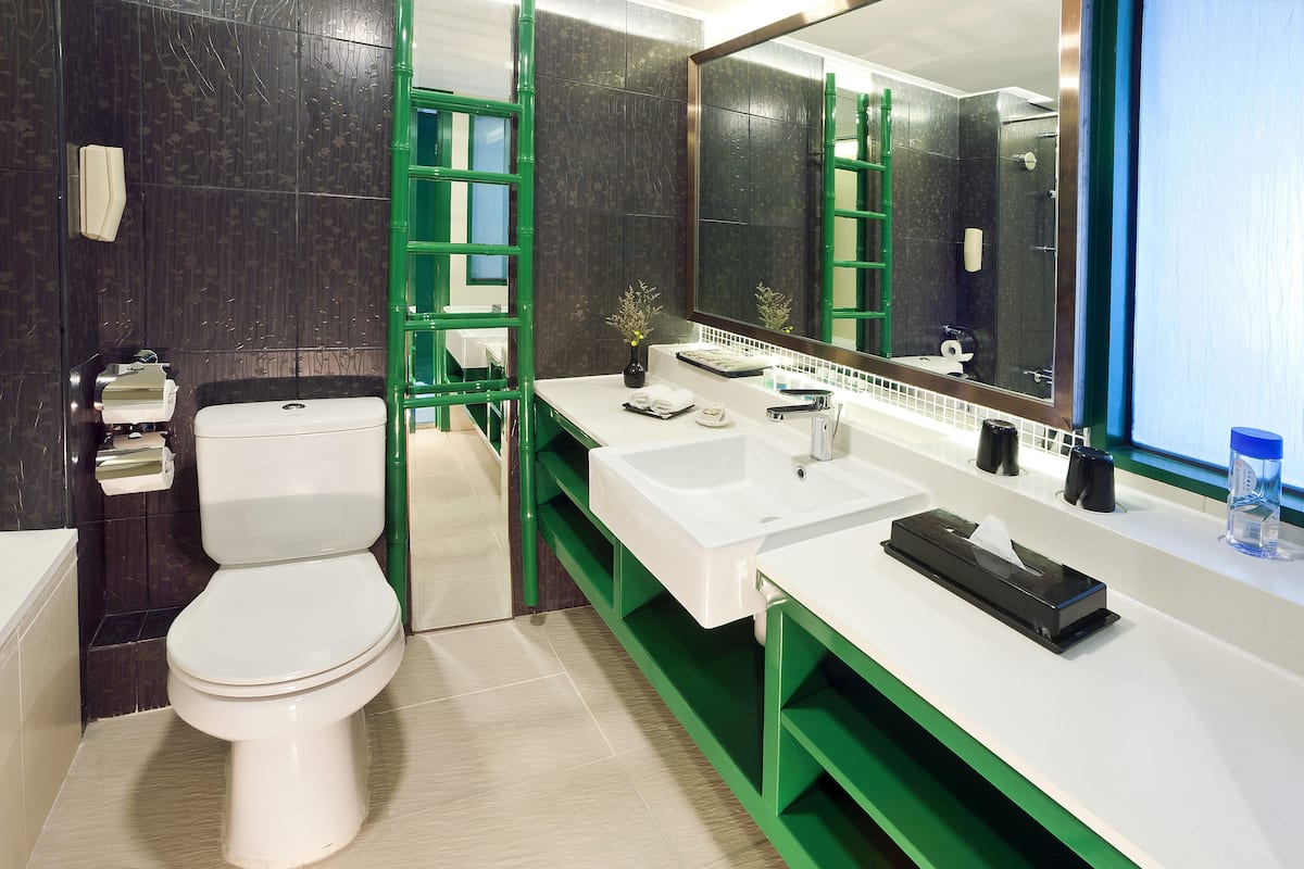 A modern bathroom with a toilet, a sink, a mirror, and a green vanity.