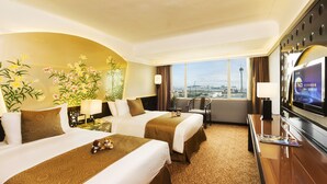 A hotel room with two beds, a TV, a desk, and a large window with a city view. - Riviera Hotel Macau (Macau)
