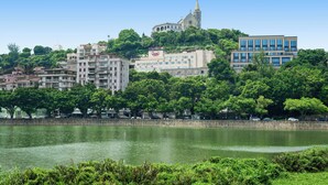 A cityscape with a prominent church on a hill, surrounded by lush greenery and modern buildings. - Riviera Hotel Macau (Macau)