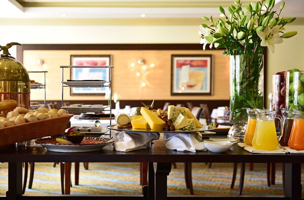 Una mesa de buffet con diversos alimentos y bebidas, como queso, frutas y jugos.