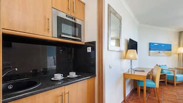 Cozinha compacta com micro-ondas, pia e área de refeições com mesa e cadeiras.