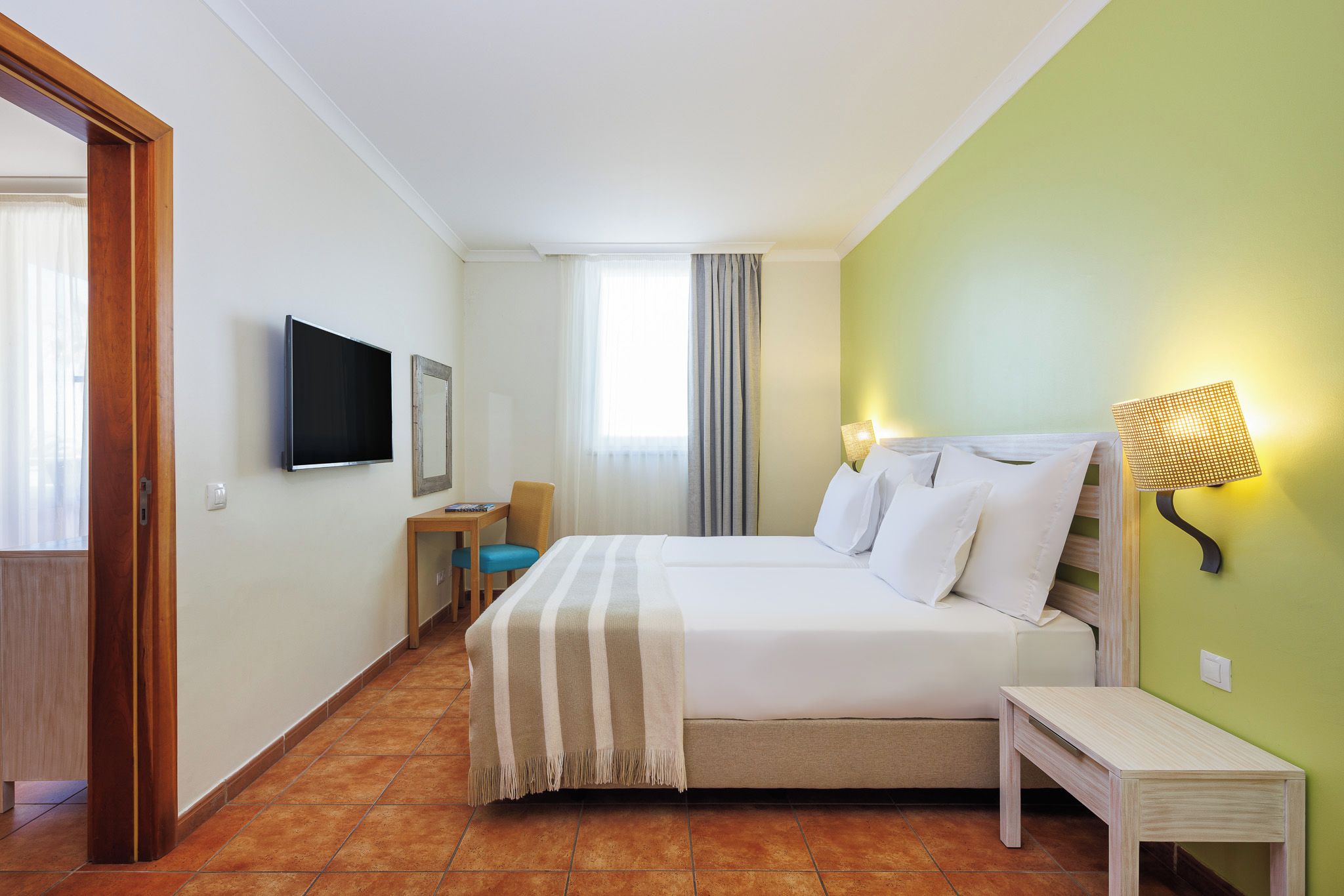 Ein Hotelzimmer mit Bett, Fernseher, Schreibtisch und Stuhl.