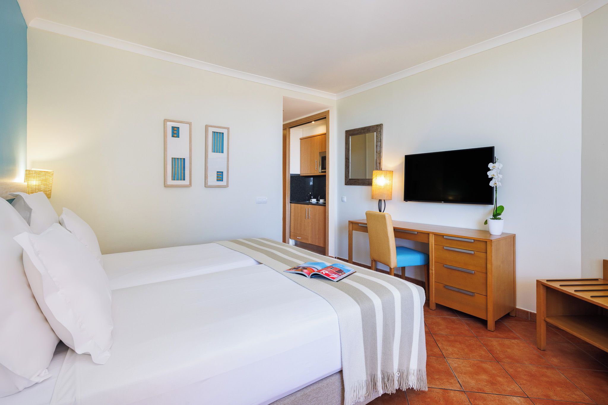 A hotel room with a bed, a desk, a chair, a television, and a mirror.