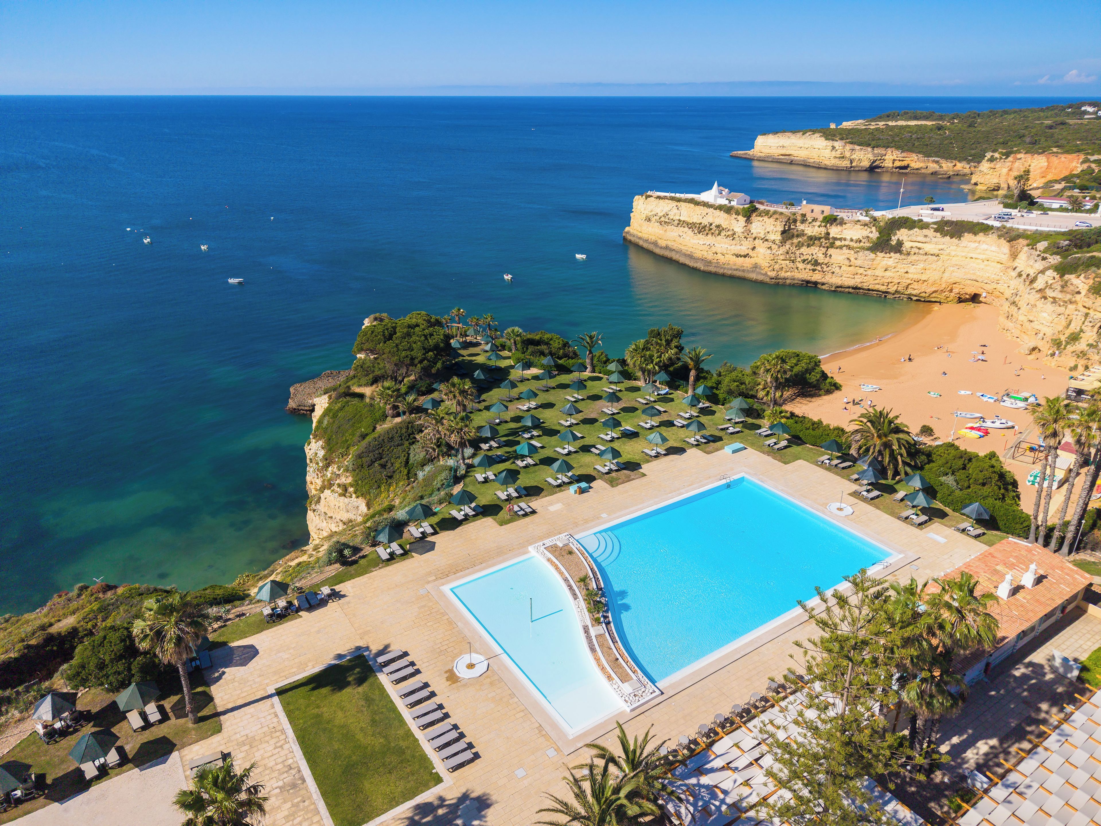 Un resort con piscina, playa y vistas al acantilado.