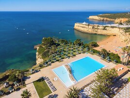 Un resort con piscina, playa y vistas al acantilado.