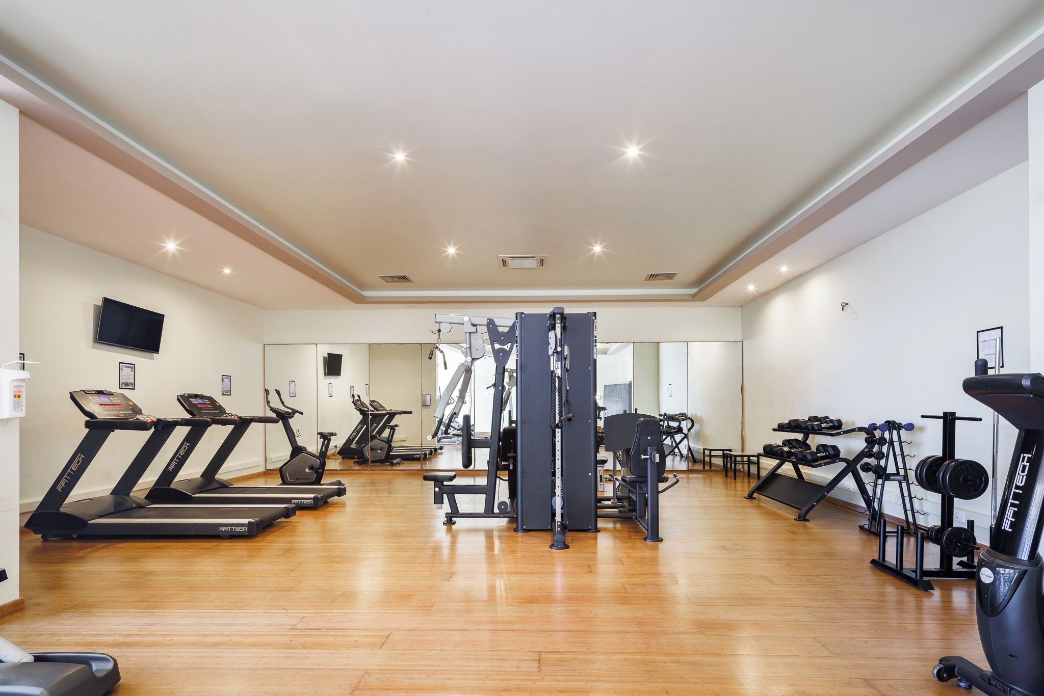 A spacious gym with treadmills, weight machines, and free weights.