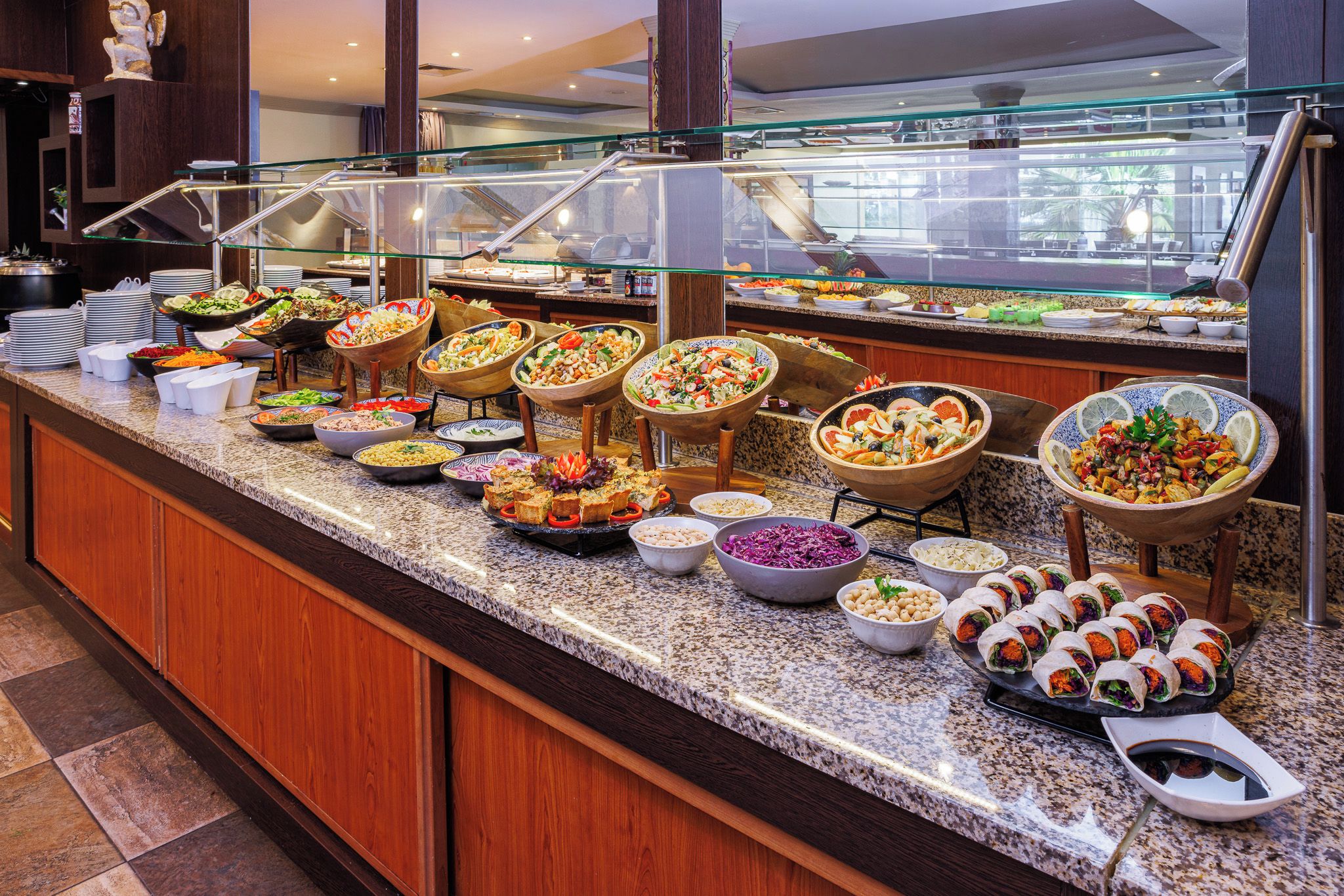 A buffet with various food options, including salads, dips, and wraps.