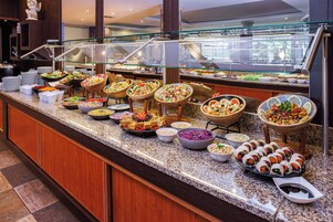 Un bufé con diversas opciones de comida, entre ellas ensaladas, salsas y wraps.