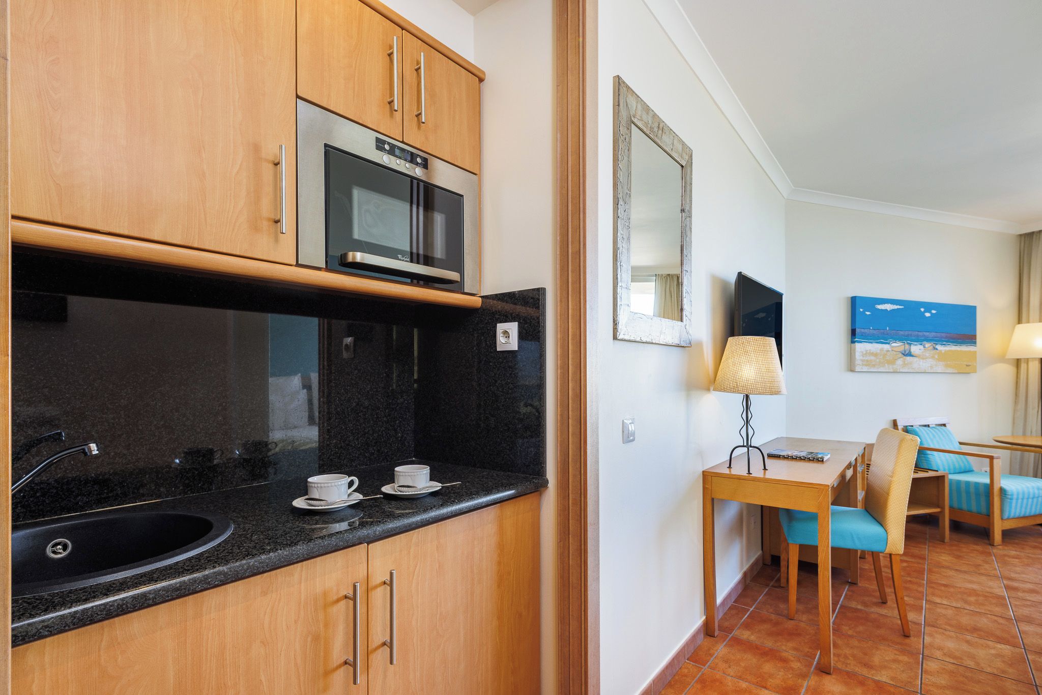 A compact kitchen with a microwave, a sink, and a dining area with a table and chairs.