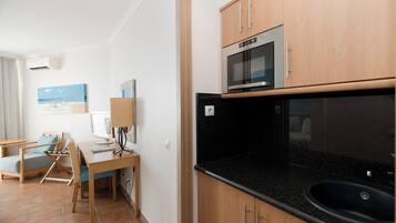 A compact kitchen with a microwave, oven, and sink. There is a dining area with a table and chairs.