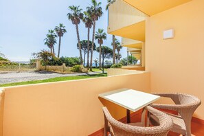 A balcony with wicker chairs and a table, overlooking a beach with palm trees. - Pestana Viking Beach & Spa Resort (Lagoa)