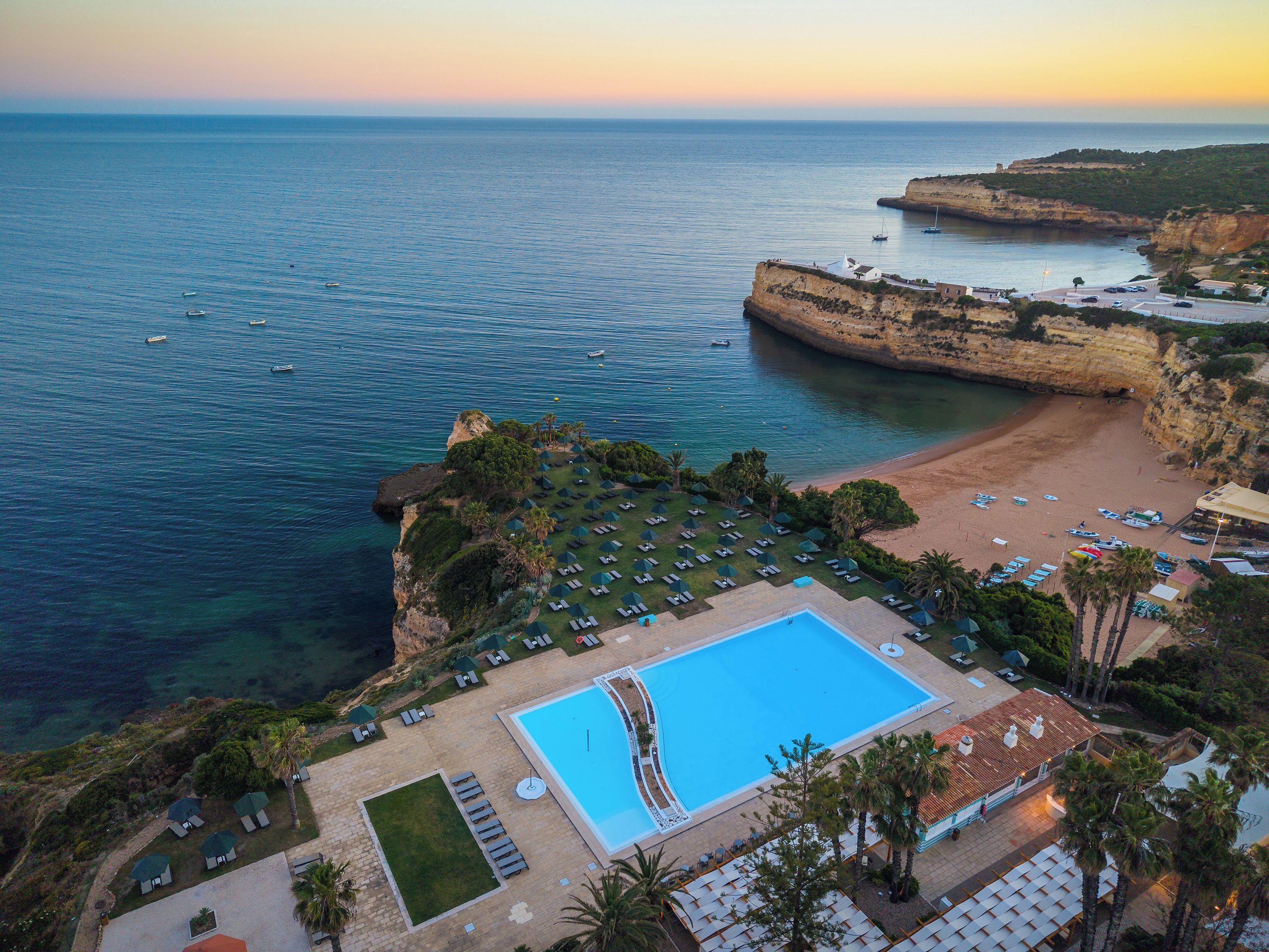 A resort with a swimming pool, beach, and cliffside views.