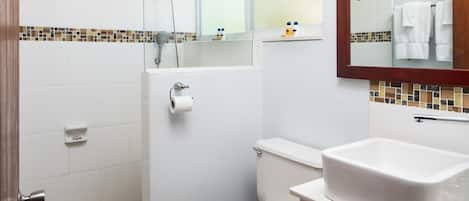 A bathroom with a shower, toilet, sink, and a mirror.