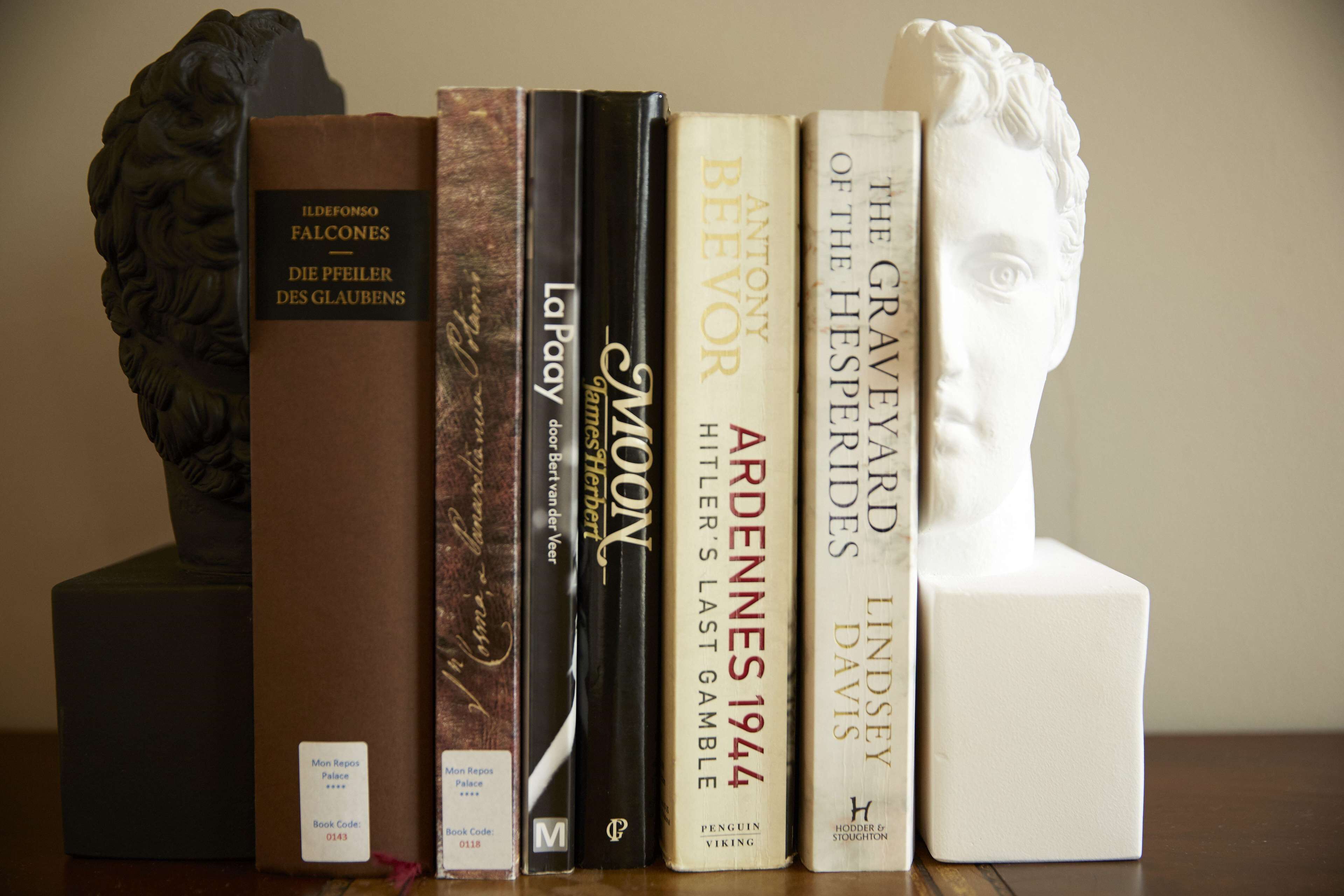 A bookshelf with books and a bust sculpture.
