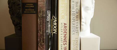 A bookshelf with books and a bust sculpture.