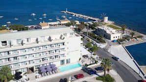 Un hotel con piscina, vista sul mare e un mulino a vento sullo sfondo.