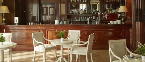 A bar area with a wooden counter, multiple chairs, and a bar stocked with bottles.