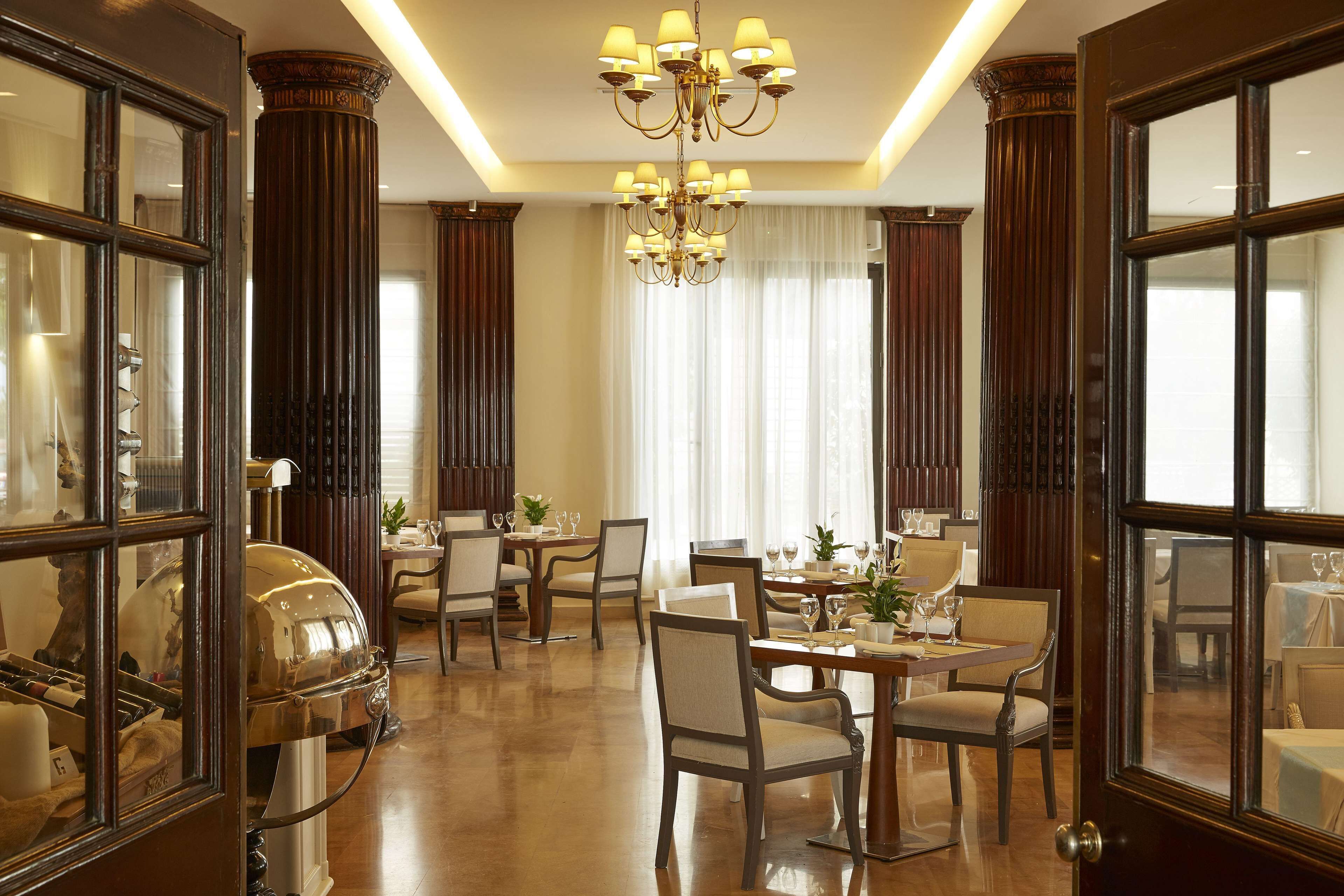 A formal dining room with a chandelier, wooden columns, and a large mirror.