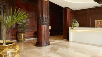 Un vestíbulo con mostrador de recepción, una columna de madera maciza y una planta en maceta.