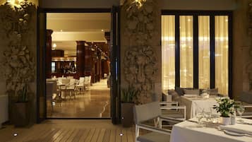 Un restaurante con suelo de madera, manteles blancos y plantas en macetas.
