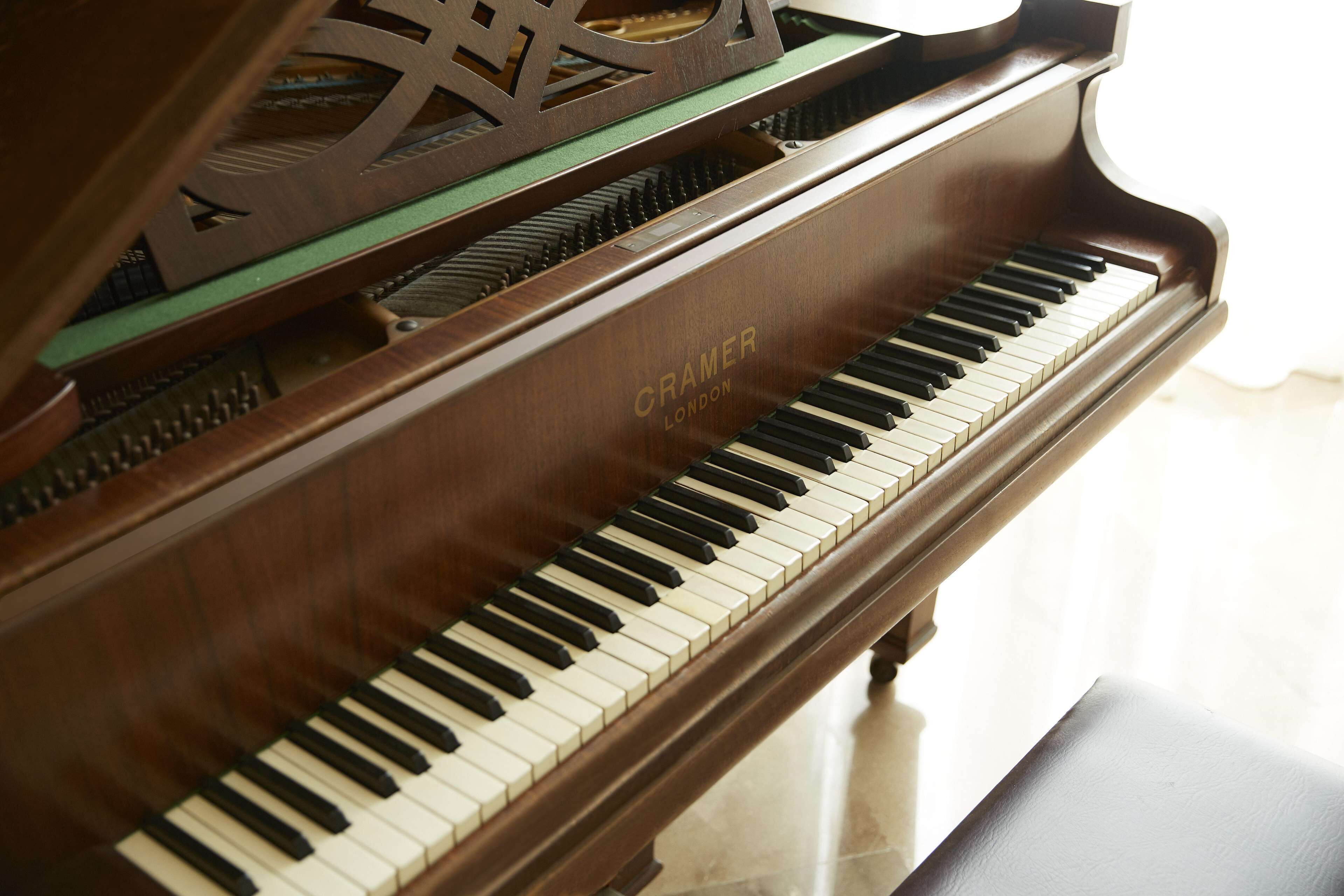 A grand piano with a wooden finish and the brand name "CRAMER LONDON" visible on the side.