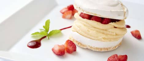 A dessert with layers of cream and strawberries on a white plate.