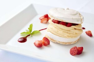 A dessert with layers of cream and strawberries on a white plate.