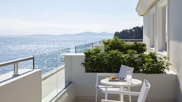 Un balcone con tavolo e sedie, vista su un corpo d'acqua e terraferma in lontananza.
