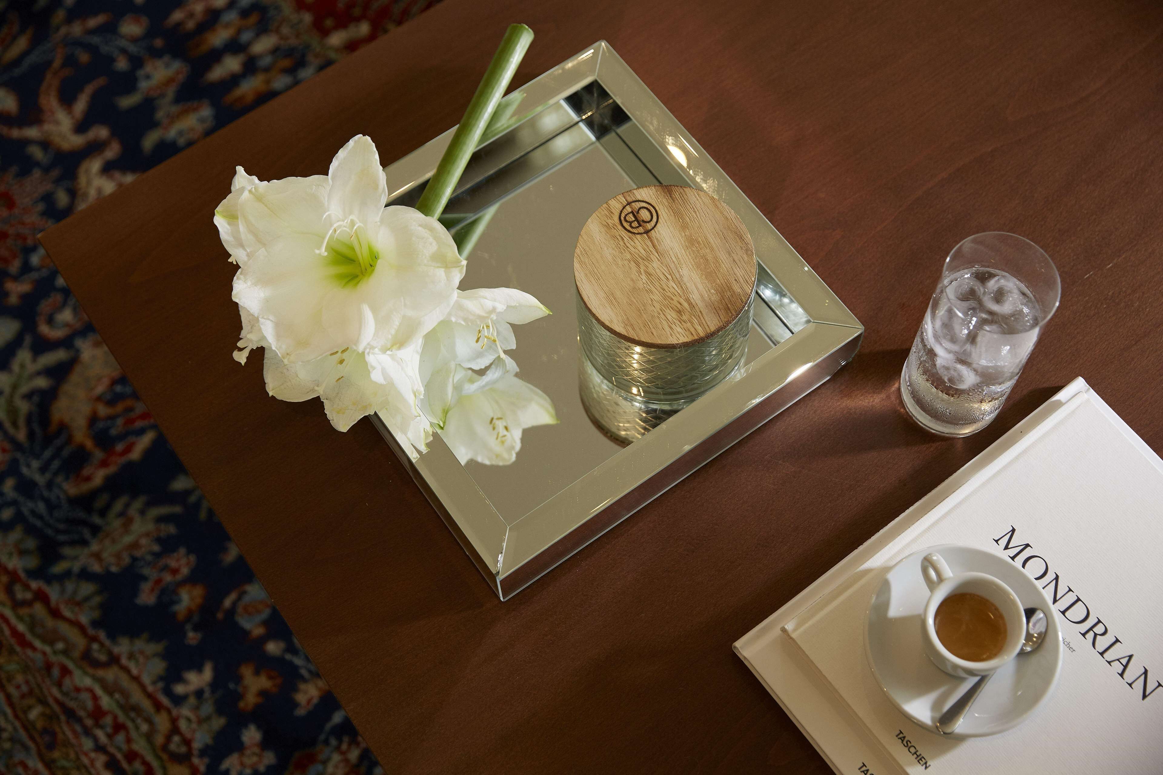 A tray with a white flower, a glass of water, and a cup of coffee on a table with a book titled "Mondrian".