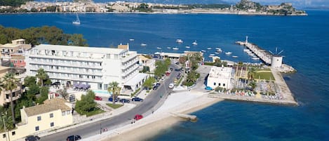 A coastal hotel with a large building labeled "Mon Repos Palace," a beach, and a marina with boats.