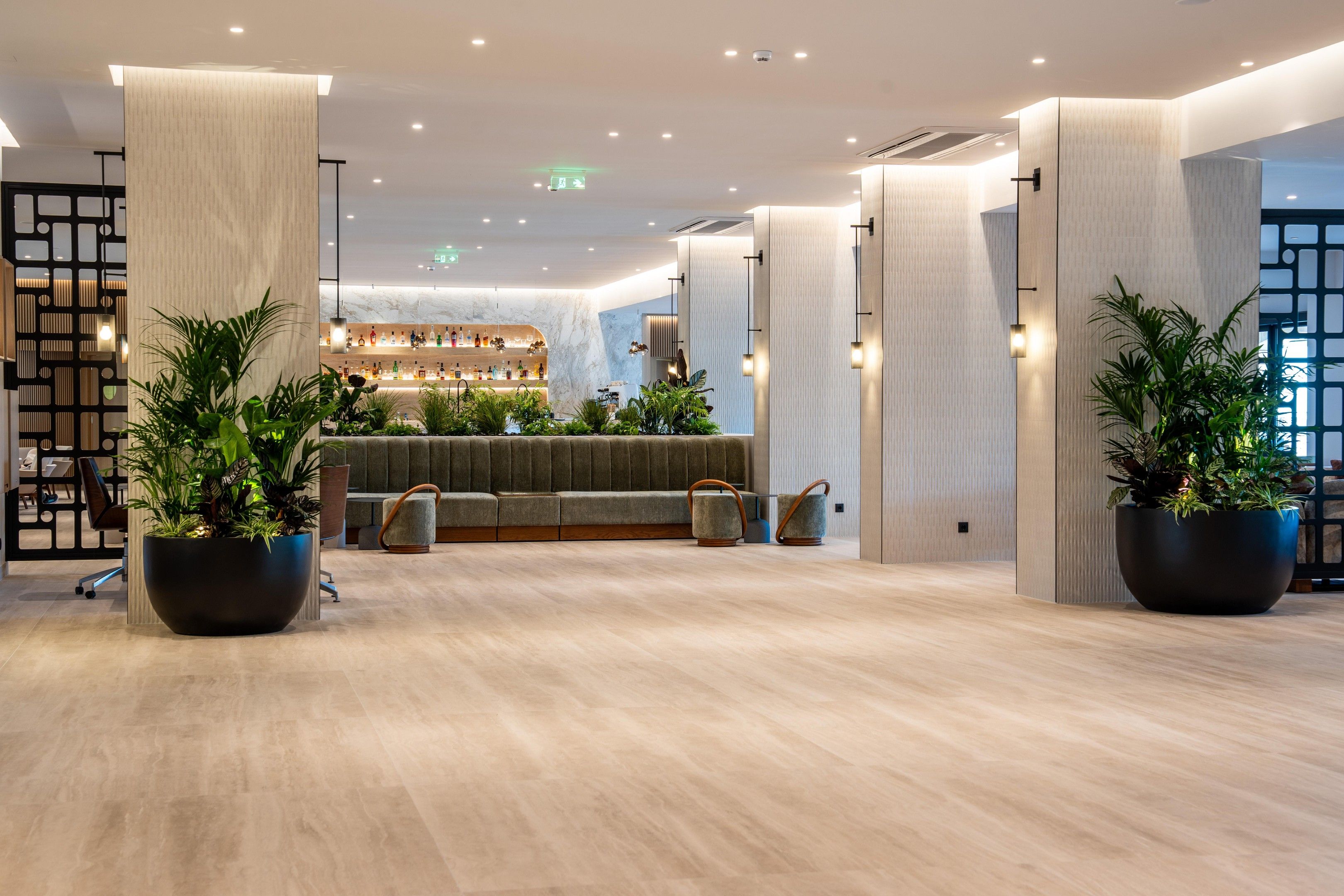 A modern lobby with a bar area, seating, and potted plants.