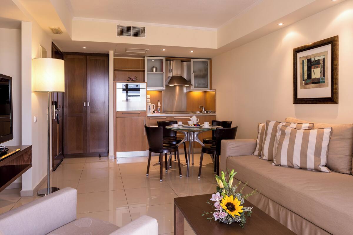 A modern living room with a sofa, coffee table, and a dining area with chairs and a table.