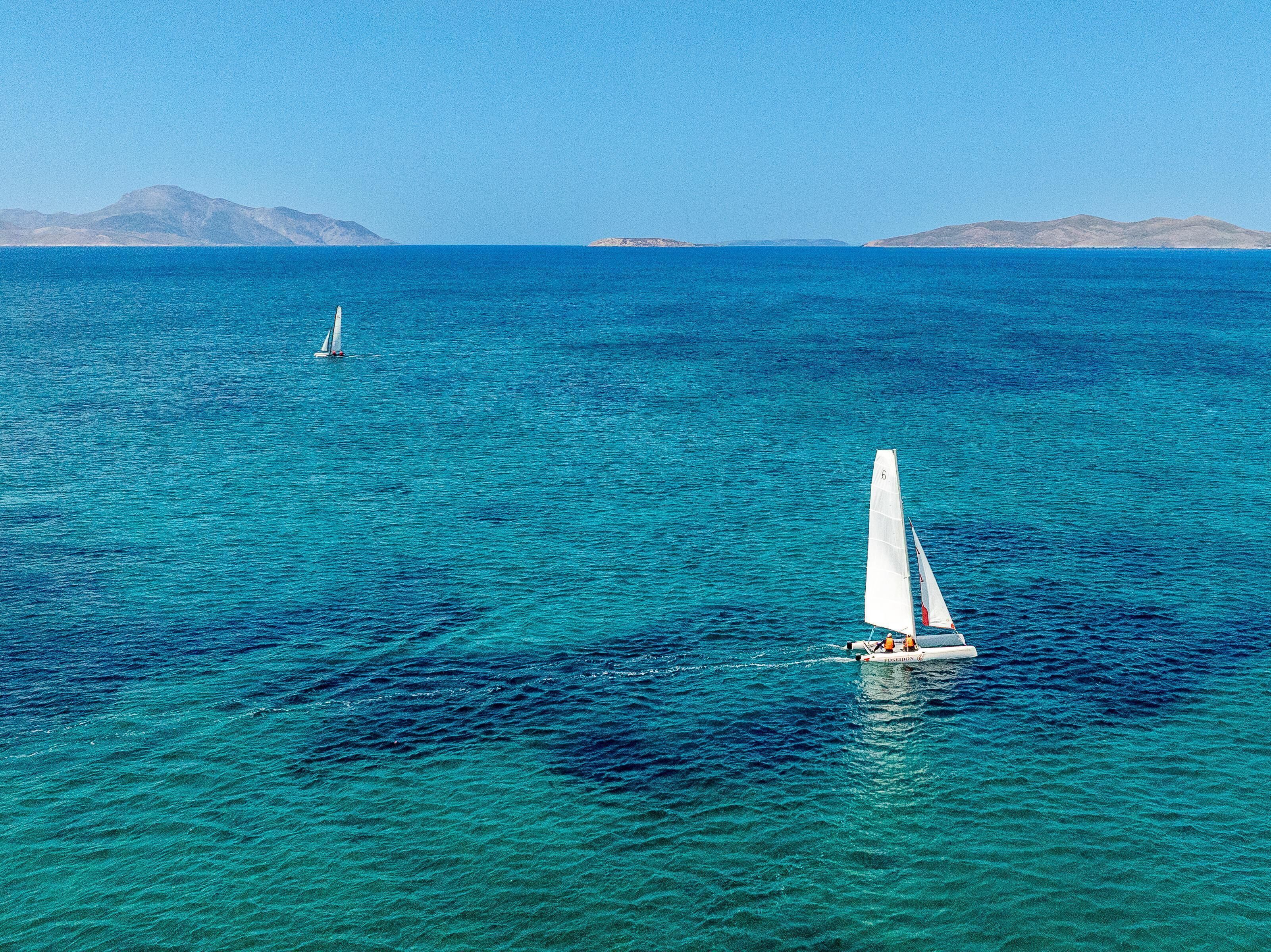Un velero en un mar tranquilo, con tierra a lo lejos.
