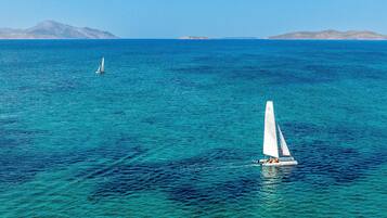Un velero en un mar tranquilo, con tierra a lo lejos.