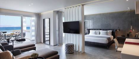 Una habitación de hotel moderna con balcón, una cama grande, televisor y escritorio.