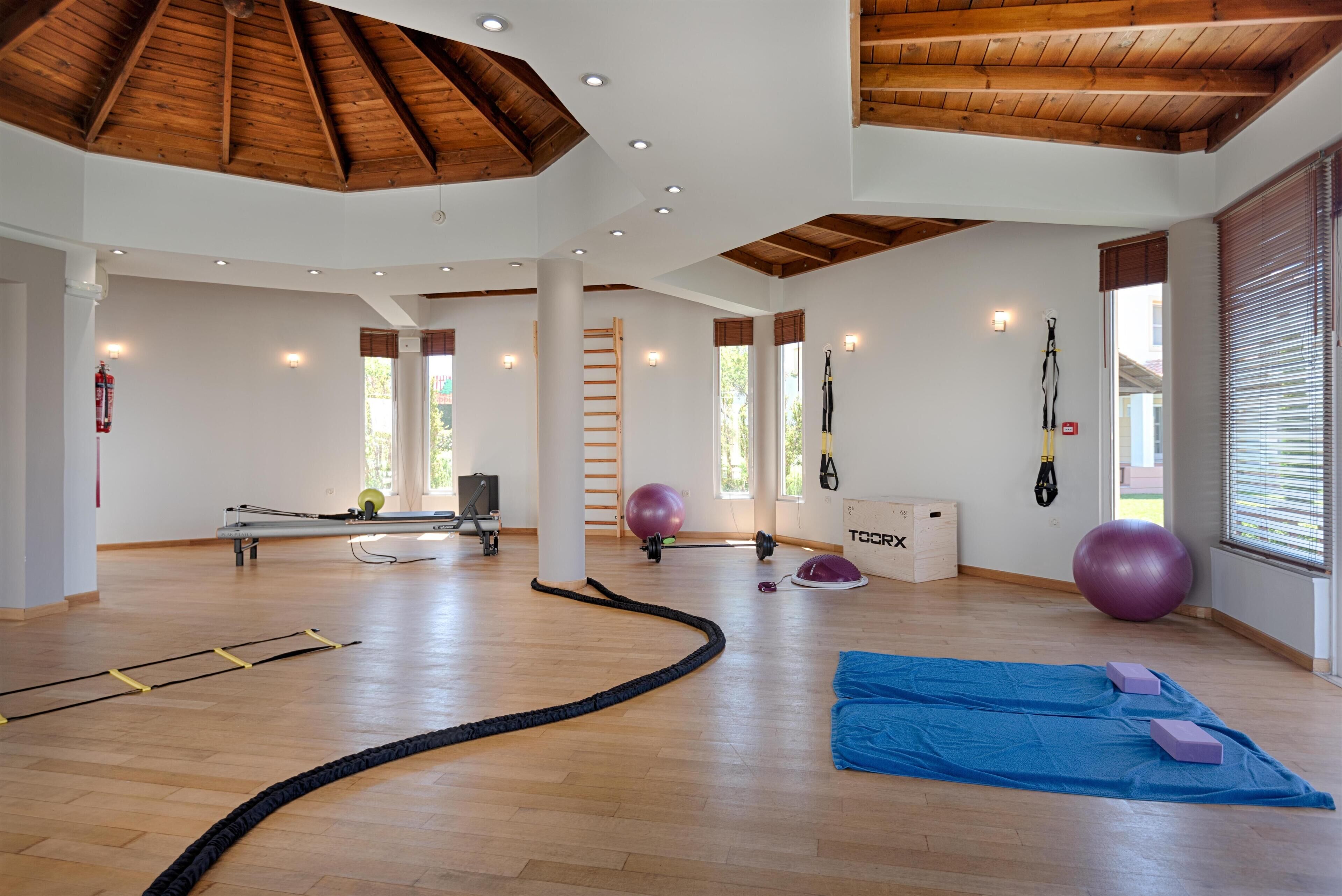 A spacious indoor gym with wooden beams, exercise balls, and a blue mat.