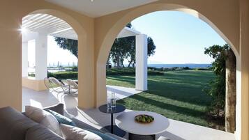 A modern outdoor seating area with a sofa, chairs, and a table, overlooking a well-maintained lawn and distant landscape.