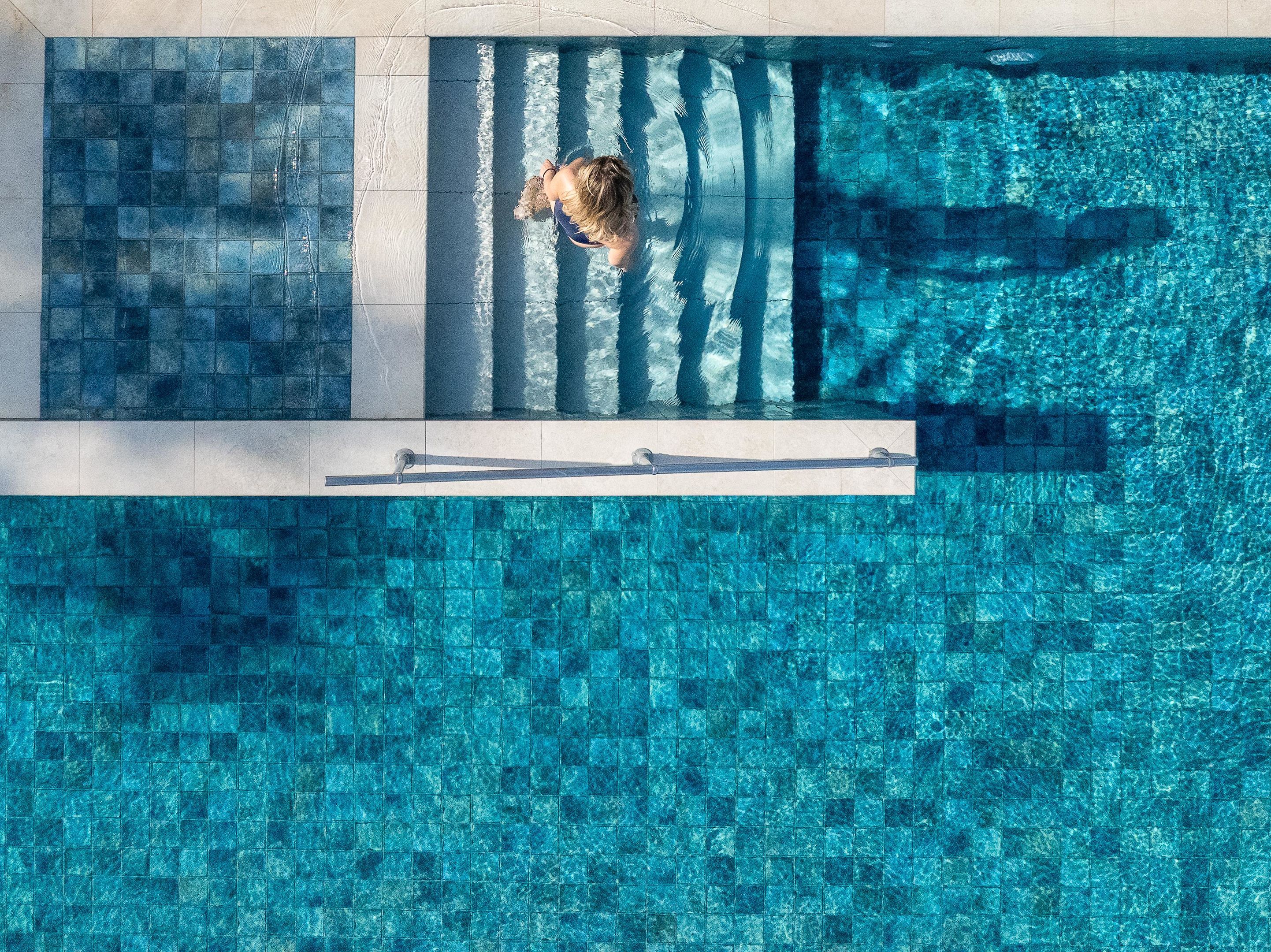 Una piscina con borde de azulejos y trampolín.