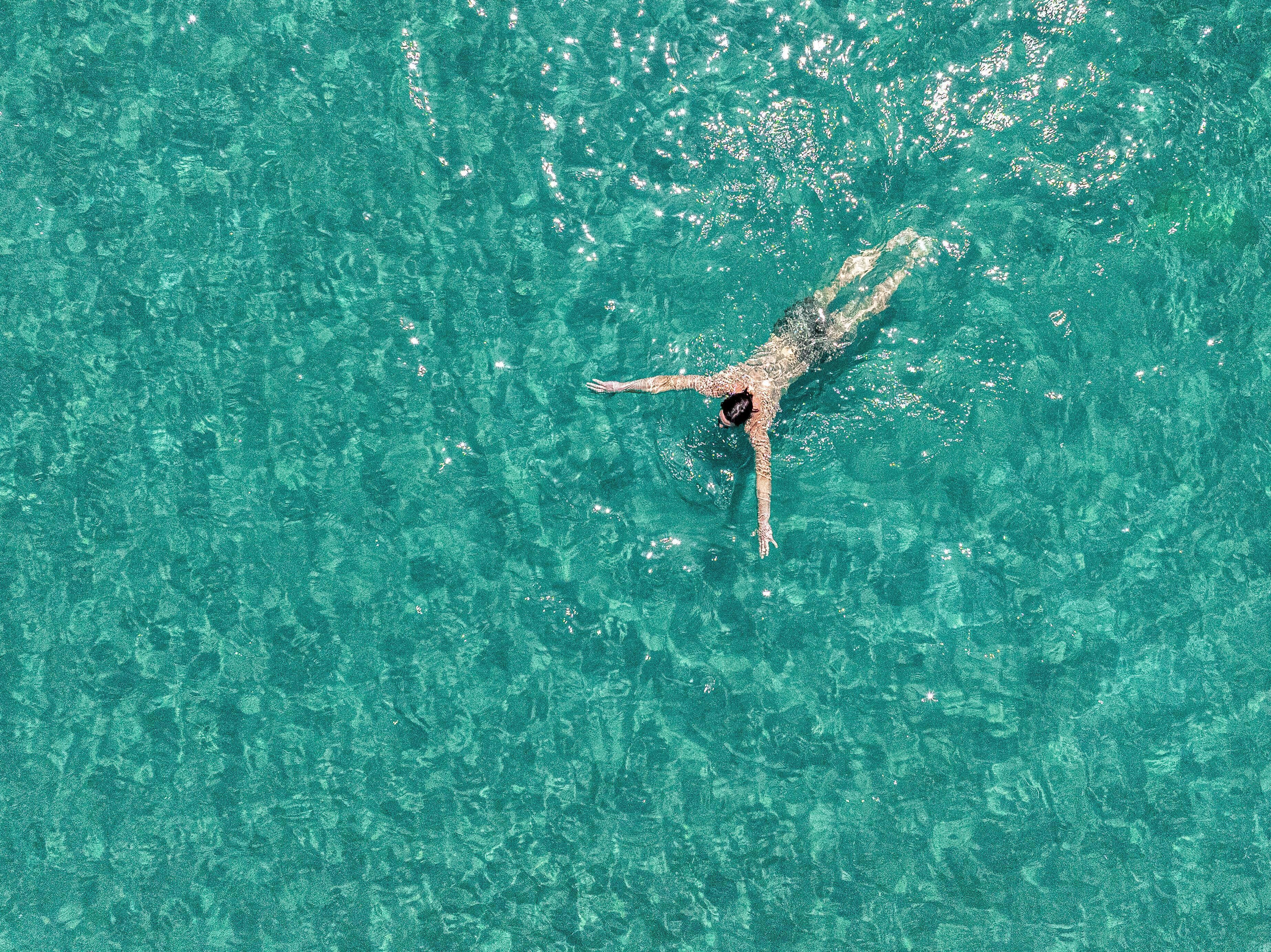 A person swimming in clear turquoise water.