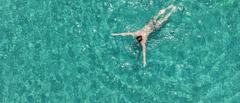 A person swimming in clear turquoise water.