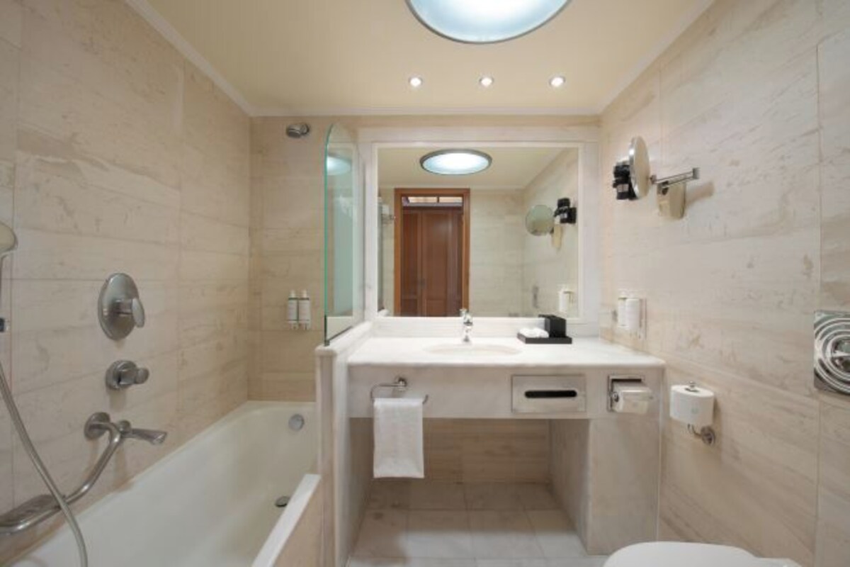 A modern bathroom with a bathtub, a sink with a mirror, and a toilet.