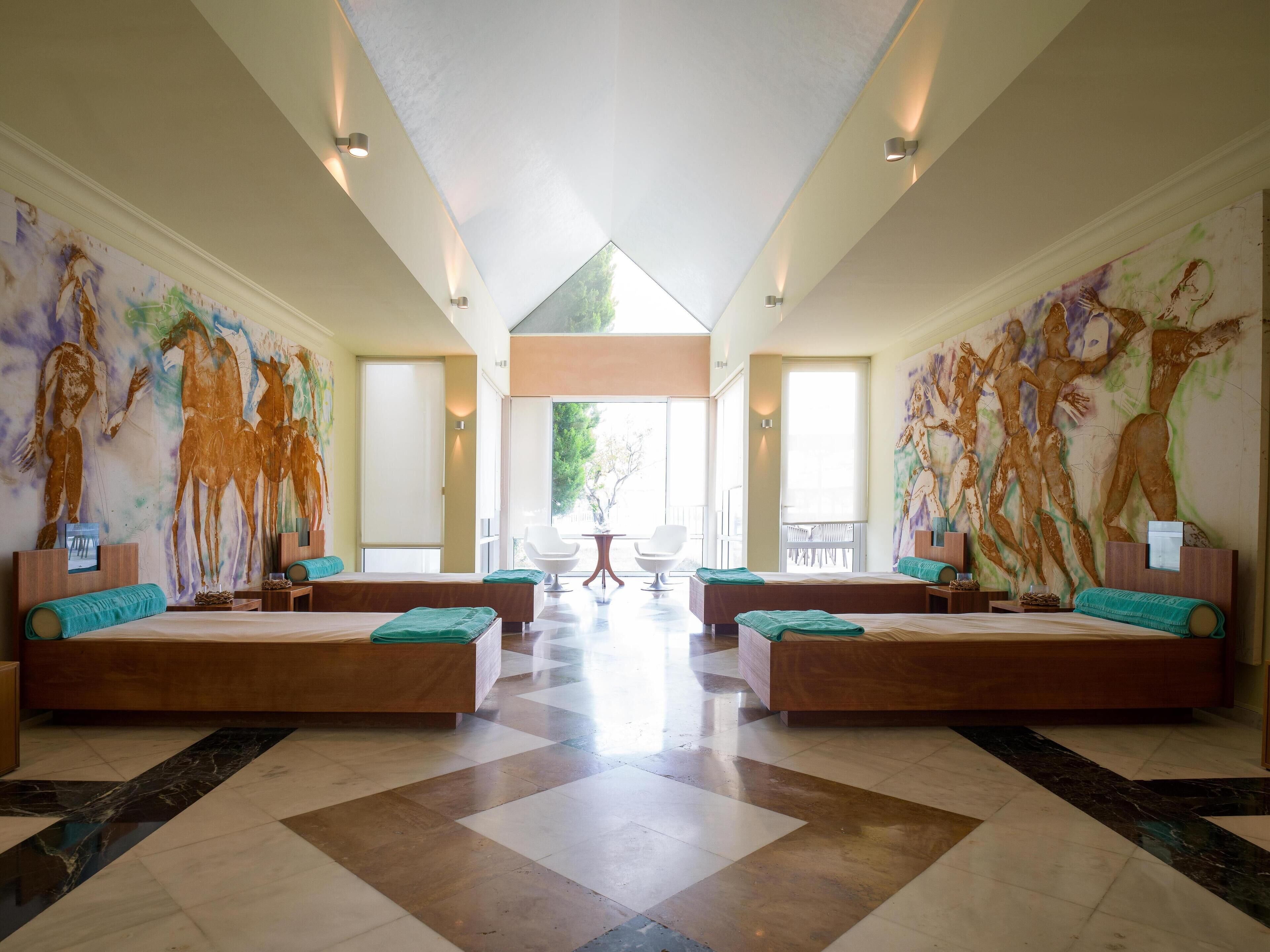 A spacious room with two large beds, a dining area, and a view of the outdoors.