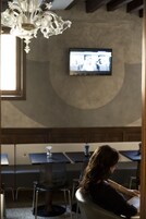 Zona pranzo con tavoli e sedie, un lampadario e un televisore montato a parete.